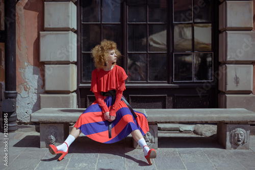 Young woman with curly hair in red retro dress. Walk around the city