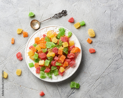 Cubes of dried apricot, kiwi, mango, pineapple and papaya on white plate. Candied fruits over gray background. Top view. photo