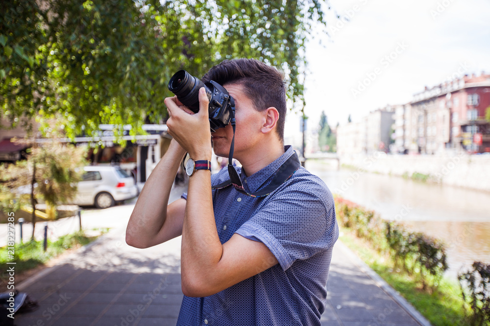 Close up view of young man with digital camera outdoors.Photographer photographing outdoor