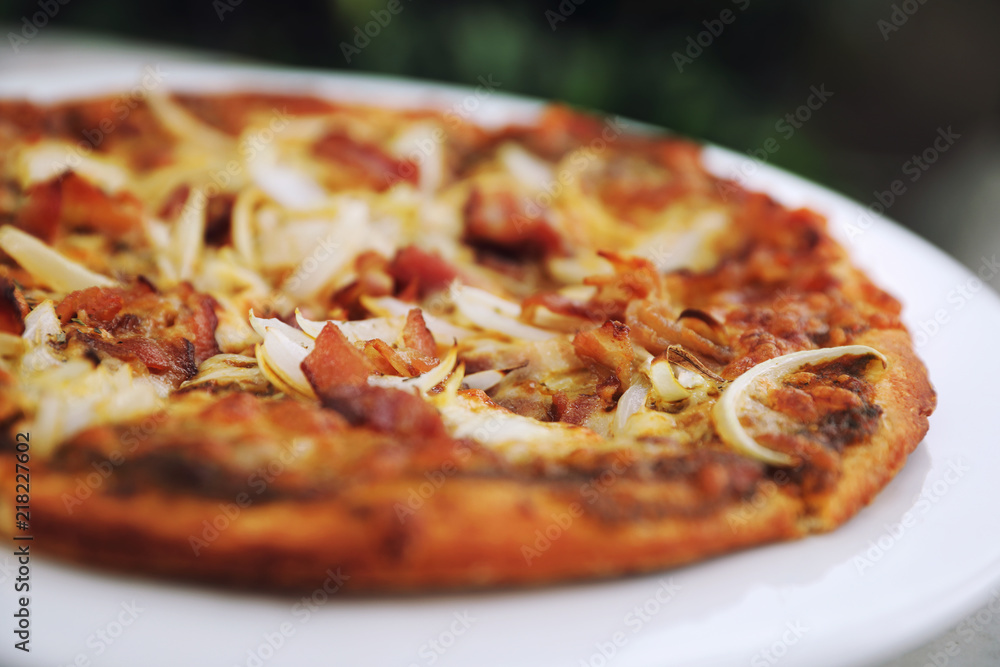 Pizza with crispy bacon onion on outdoor table