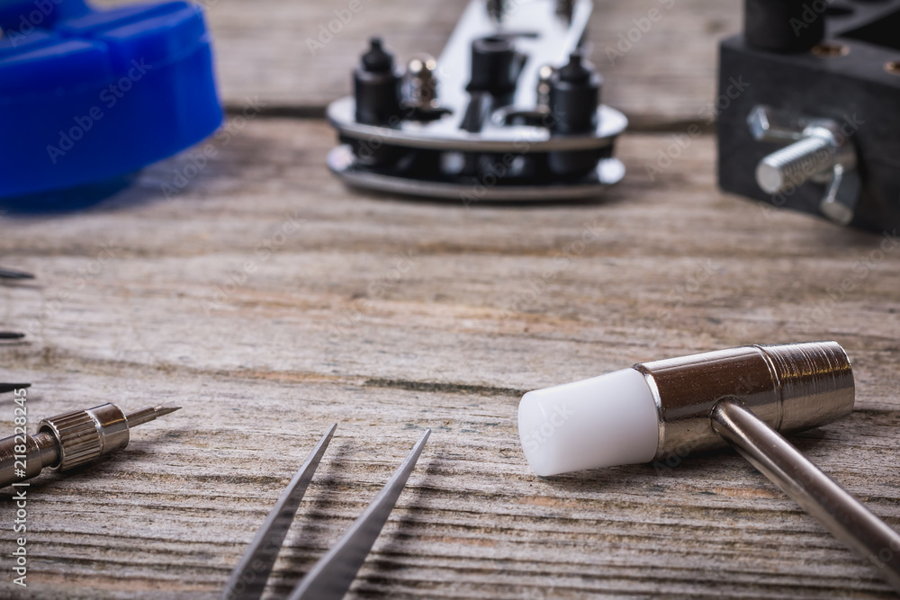 Set of watchmaker tools isolated on a rough wooden board Set of watchmaker tools isolated on a rough wooden board