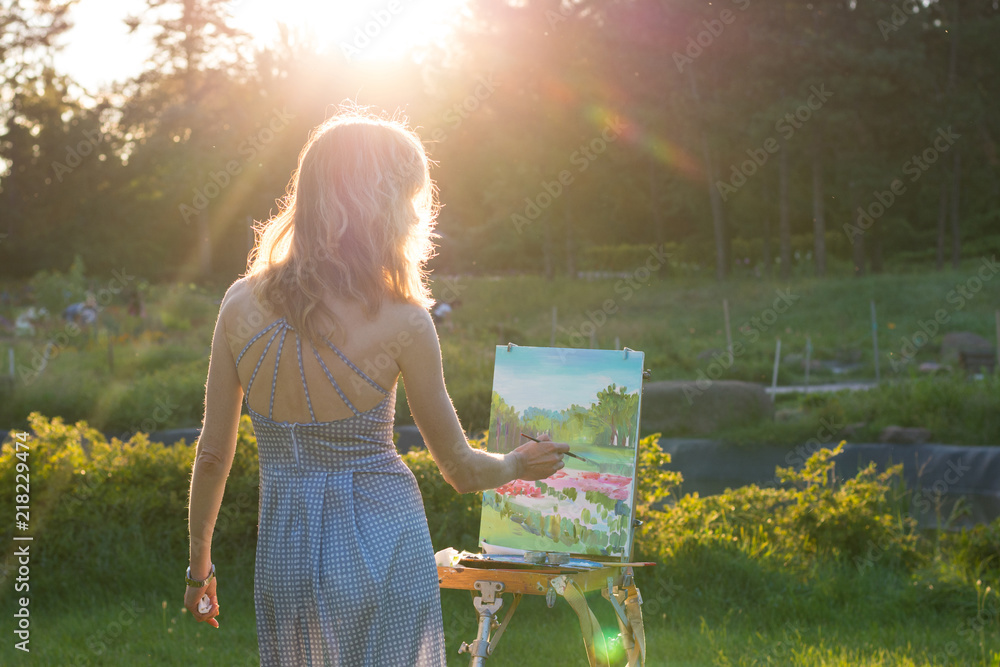 Obraz premium The painter paints oil paintings in the garden at sunset