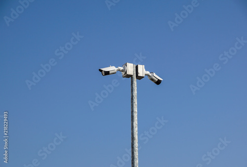 CCTV surveillance security camera on a black pole with blue sky background