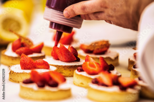 The chef in the kitchen prepares strawberry dessert.Close up