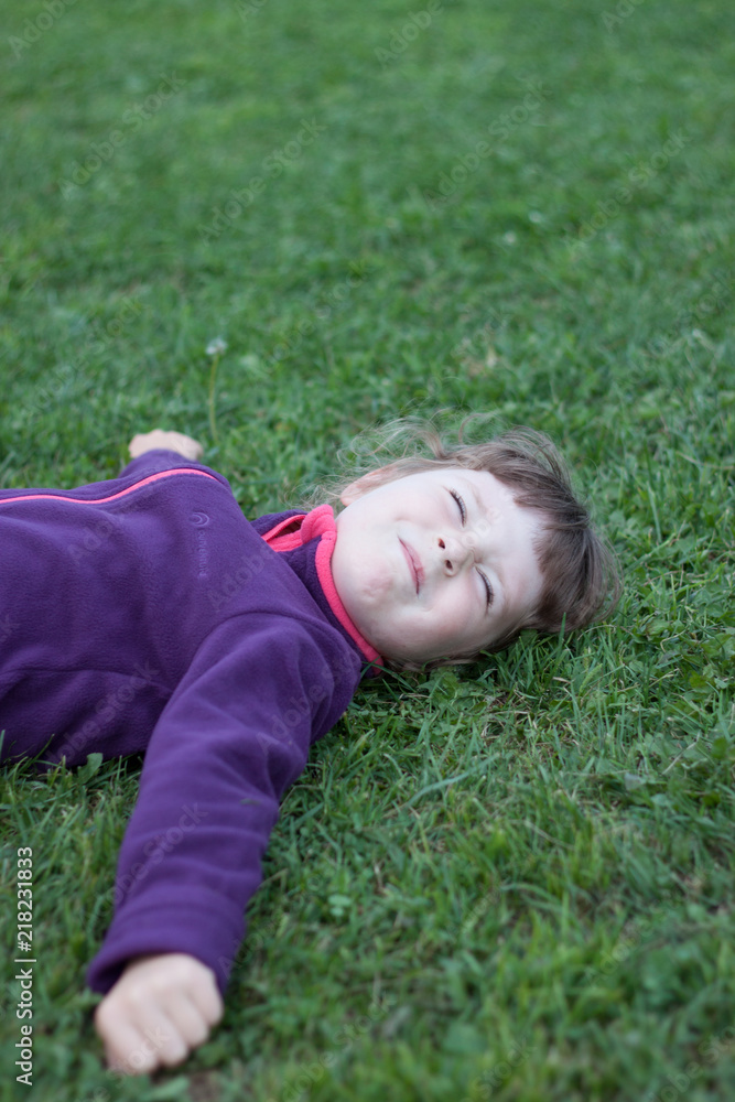Little kid playing in garden lying in grass Little kid playing in garden lying in grass