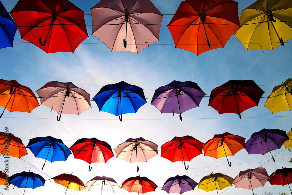 A row of colorful umbrellas with blue sky background. 