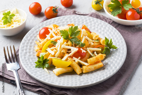 Macaroni, pasta in tomato sauce and cheese in a plate on a wooden table