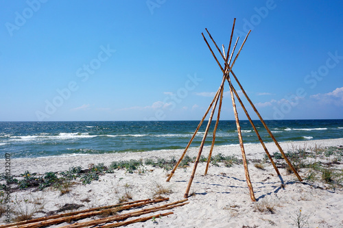 Foundation for Indian wigwam lodge or teepee made of pine wood at the seashore at summer. travel concept. copyspace