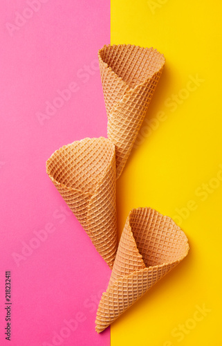 Three empty ice cream cones on a double colored backgrounds viewed from above. Waffle ice cream cone. Top view. Flat lay