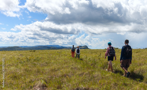 Group of young people walking across a field in a mountainous area