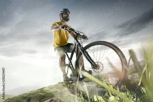 Fototapeta Naklejka Na Ścianę i Meble -  The young fit men in helmet conquering mountains on a bicycle. The bike, nature, bicycle, sport, cycle, extreme, lifestyle, adventure and sport concept