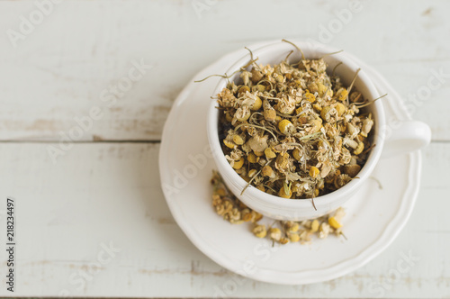 Dried chamomile flowers. Herbal tea in a white cup  top view  wooden background