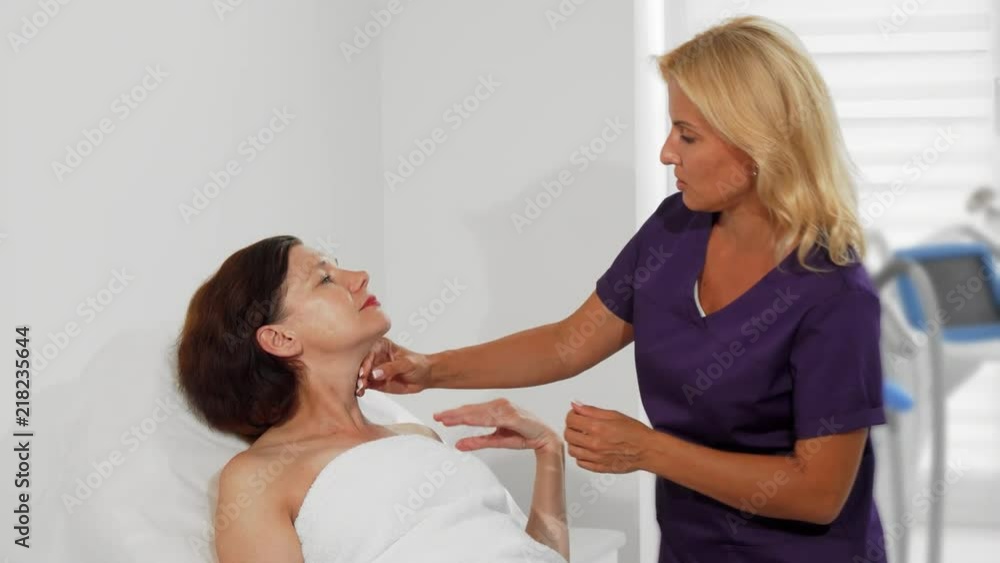 Professional beautician working at her clinic, examining face skin of her mature female client before starting treatment procedures. Mature woman talking to her cosmetologist. Beauty, skin concept. Professional beautician working at her clinic, examining face skin of her mature female client before starting treatment procedures. Mature woman talking to her cosmetologist. Beauty, skin concept.