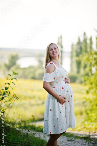 Blonde pregnant mother in meadow field. Happy moments of pregnancy.