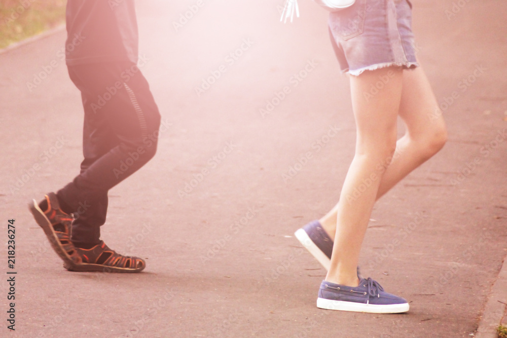 Boy and girl walking on the road in sneakers, feet