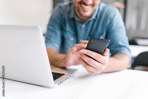 Man using smartphone and laptop. Close-up.
