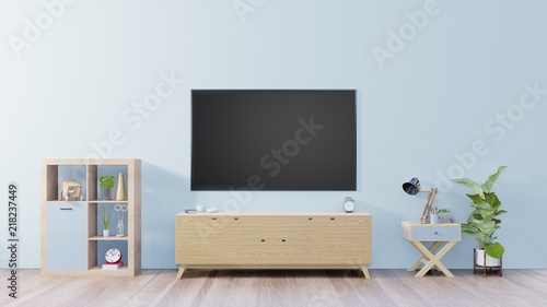 TV on cabinet in empty interior room ,blue wall with wood shelf,lamp ,plants and table wood ,3d rendering