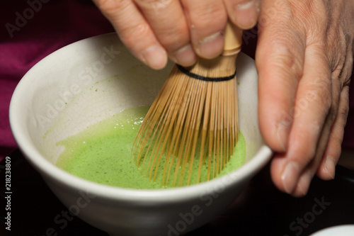 Close-up of mixing matcha tea using a chasen wisk and bowl during a tea ceremony