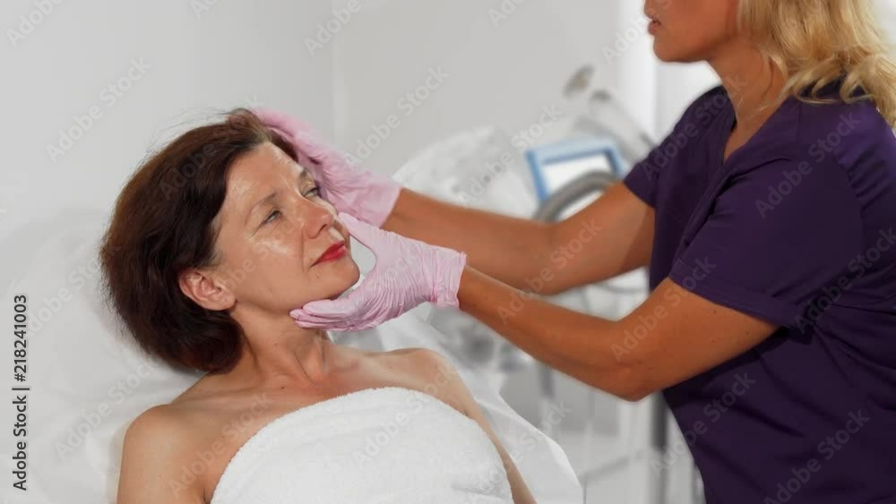 Cropped shot of a senior woman preparing to get facial treatment at the beauty clinic, getting her skin examined by cosmetologist. Professional dermatologist checking face skin of female patient. Cropped shot of a senior woman preparing to get facial treatment at the beauty clinic, getting her skin examined by cosmetologist. Professional dermatologist checking face skin of female patient.