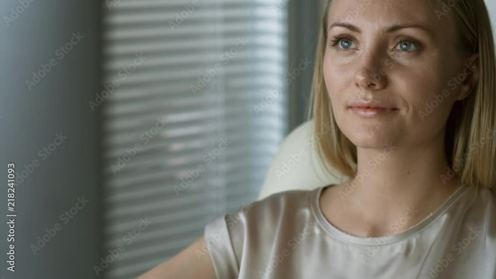 Close up face of blonde female employee sitting at desk in office and working on desktop computer Close up face of blonde female employee sitting at desk in office and working on desktop computer