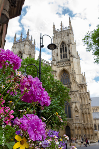 Beautiful flowers and lamp post in the foreground with York Minster Cathedral in the background on a summer day in Yorkshire, England UK.