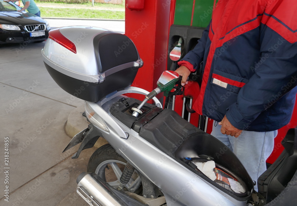 Ein Mann füllt den Tank seines Motorrollers mit Benzin an einer Tankstelle
Ein Mann füllt den Tank seines Motorrollers mit Benzin an einer Tankstelle