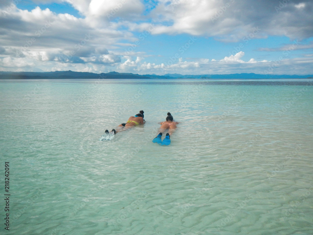 two girls in bikini lying in the water ready for snorkeling