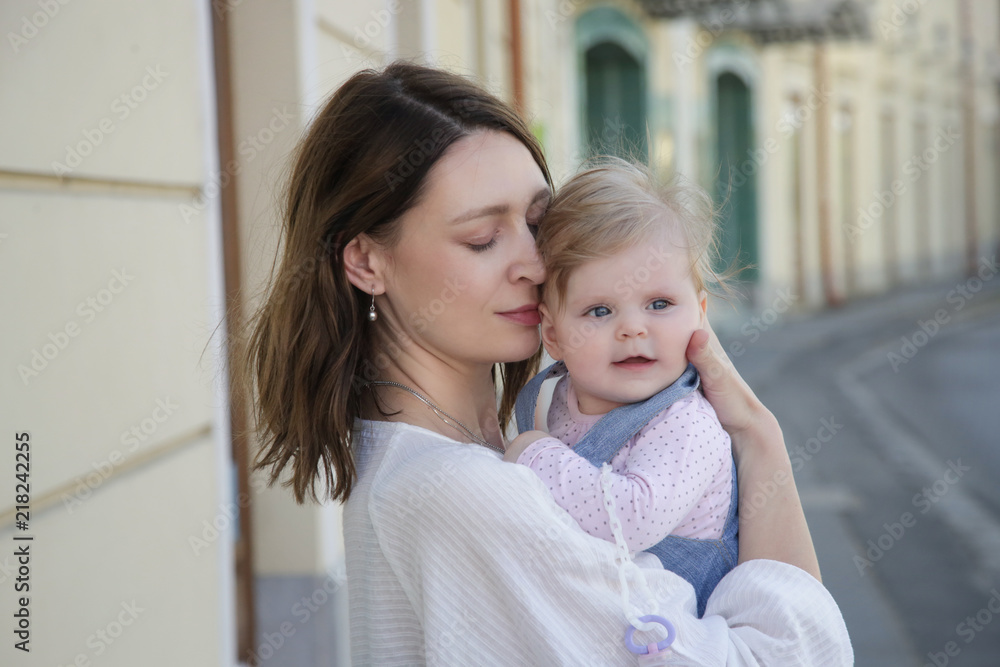 Young mother with her baby girl on the street, candid portrait image, natural lighting, family life concept
Young mother with her baby girl on the street, candid portrait image, natural lighting, family life concept