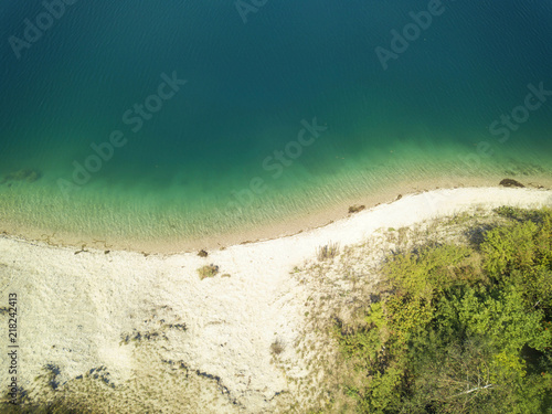 The blue-green transparent waters and the white sand shore of Hollernsee  Bavarian lake