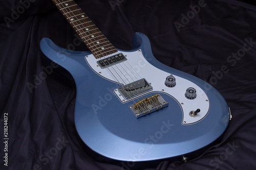 Blue electric guitar on black fabric background