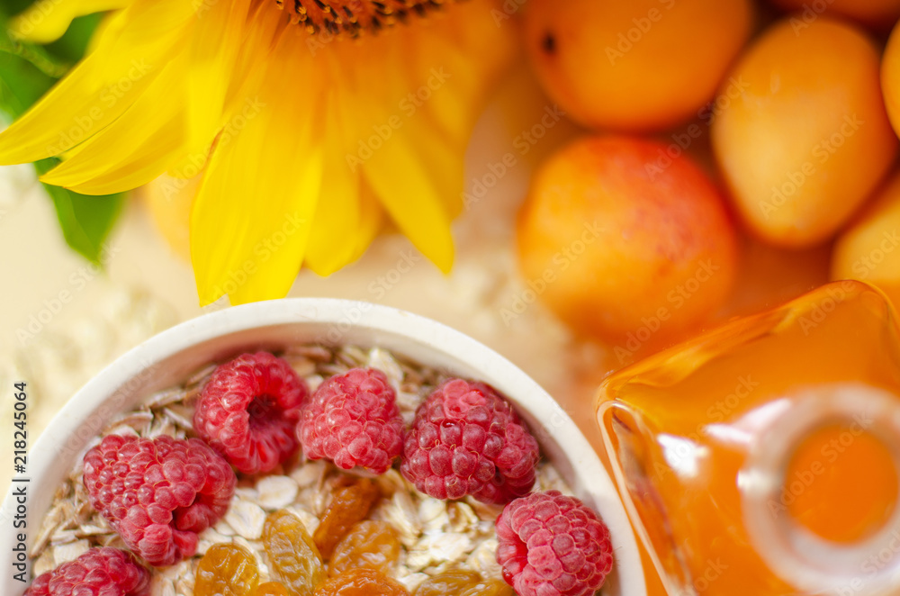 Healthy breakfast. White plate of oatmeal with dried apricots and raspberries, a glass of an apricot juice and fresh apricots on a white table. Healthy breakfast. White plate of oatmeal with dried apricots and raspberries, a glass of an apricot juice and fresh apricots on a white table.