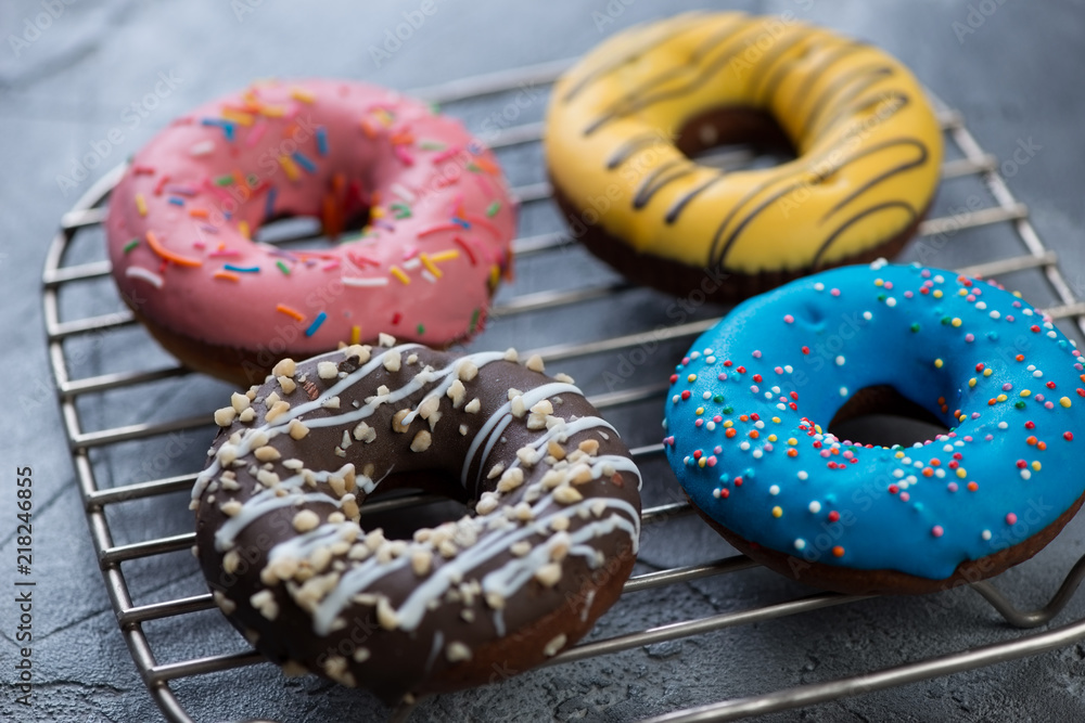 Closeup of four freshly cooked different donuts on a metal cooling rack, selective focus, studio shot Closeup of four freshly cooked different donuts on a metal cooling rack, selective focus, studio shot
