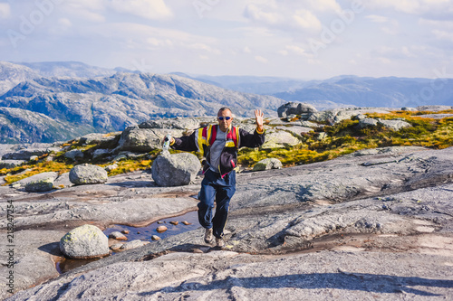 Portrait of a extreme plan travel for the handsome old man on the stone of the kjerag in the mountains kjeragbolten of Norway, selfie on a smartphone holding in your freedom hand