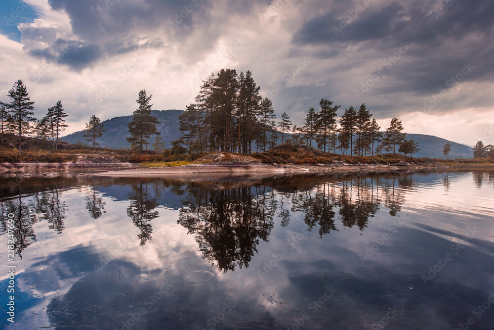 Fototapeta premium Landscape travel on the way to the stone of the kjerag in the mountains kjeragbolten of Norway, reflection of trees in the lake on the Sunset