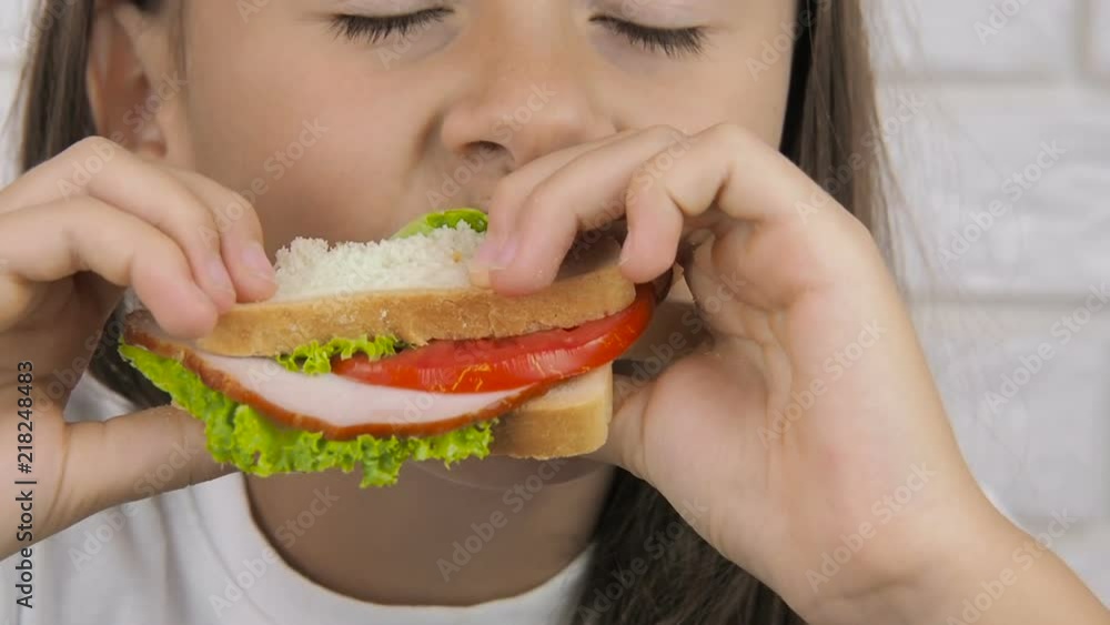 Child with a sandwich. The girl is eating a sandwich for breakfast. Child with a sandwich. The girl is eating a sandwich for breakfast.