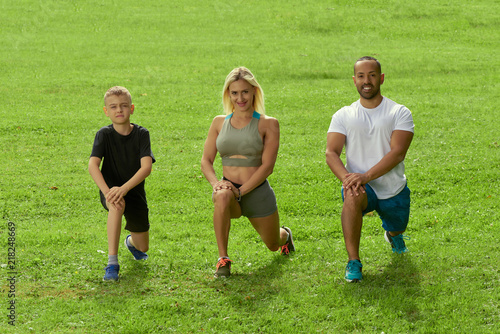 Sports multinational family; mother, father and his son doing sport exercises together outdoor