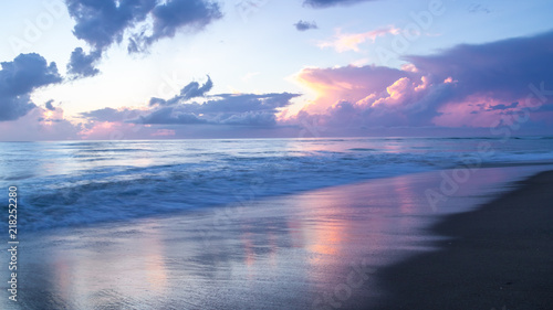 Sunrise colors in the sky, clouds, ocean and wet sand. Long exposure creates a softness and motion blur in the sea and surf. 