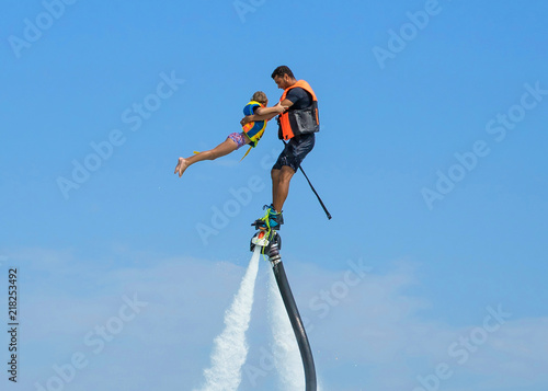 Father and his daughter posing at new flyboard at Caribbean tropical beach. Positive human emotions, feelings, joy. Funny cute child making vacations and enjoying summer.