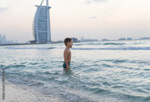 Portrait smiling little baby boy playing in the sea, ocean. Positive human emotions, feelings, joy. Funny cute child making vacations and enjoying summer. Sunset Dubai beach.