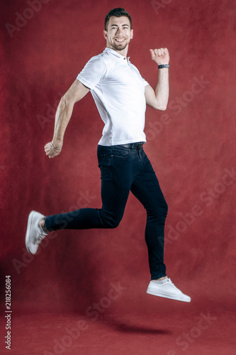 Jumping man happy excited. Funny portrait on young casual male male model in humorous jump on white background. © Виталий Давыдов