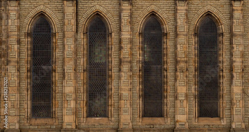 Repeating facade of stone-brick church in England with arched windows