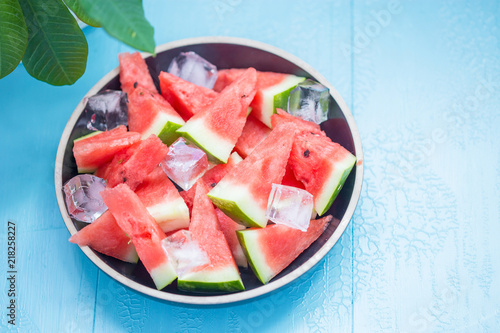slices of watermelon in a plate with ice on a blue background