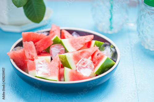 slices of watermelon in a plate with ice on a blue background