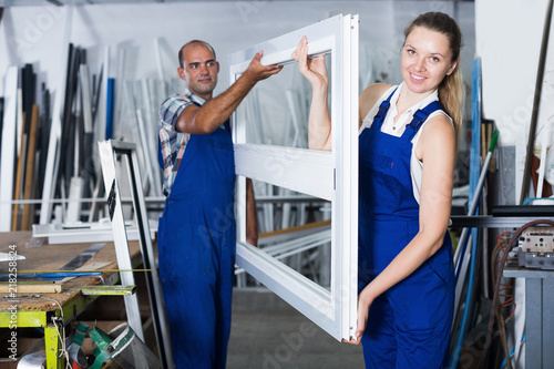 Two workers with window frame in assembly shop