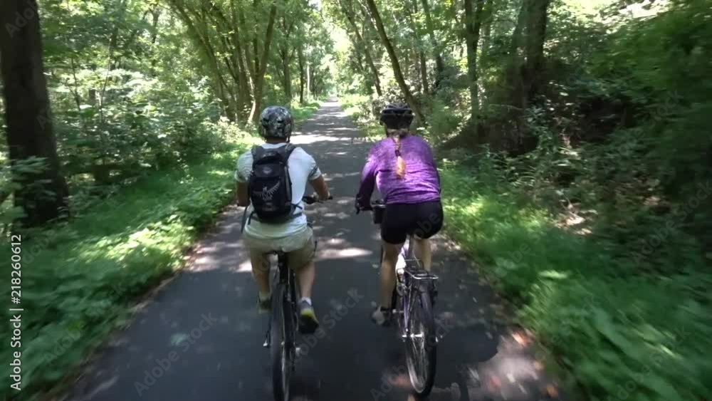 Close behind a teen boy and his mature mother on a paved rail trail in a forest near Hancock, Maryland.