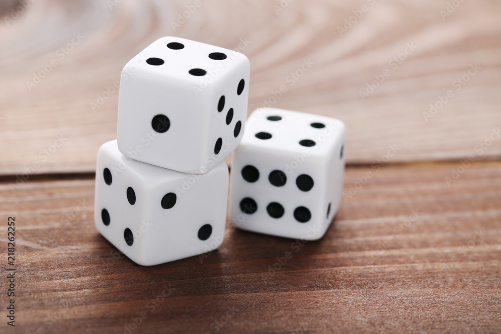 White dice on brown wooden table White dice on brown wooden table