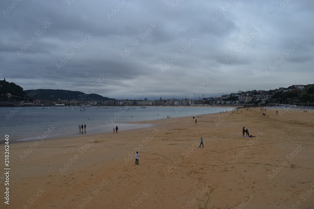Playa y zona costera de una ciudad en un día nublado.