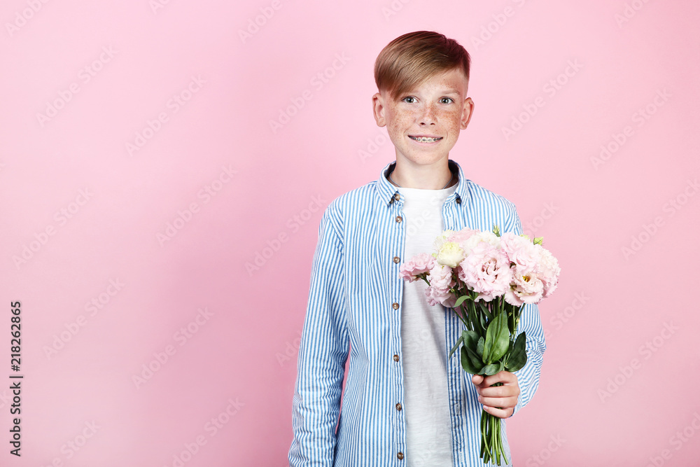 Beautiful young boy with eustoma flowers on pink background Beautiful young boy with eustoma flowers on pink background