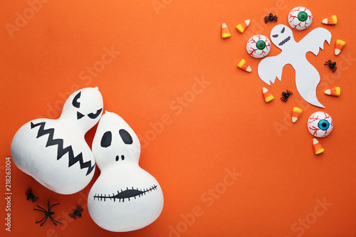 Halloween candy corns with ghost and pumpkins on orange background