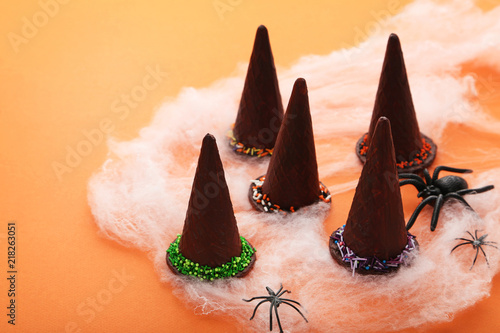 Chocolate halloween hats with spiders on orange background